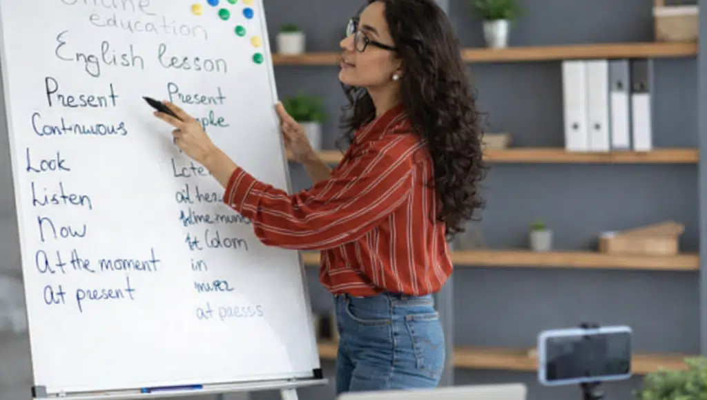 Online spoken English class with trainer explaining grammar using whiteboard