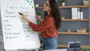 Online spoken English class with trainer explaining grammar using whiteboard