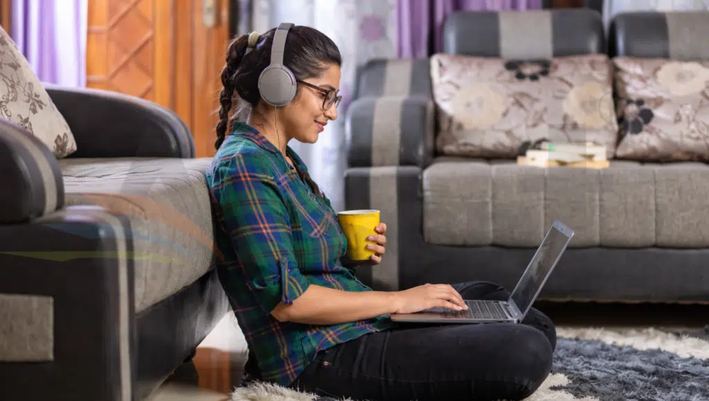 Young woman attending an online English class from home using a laptop and headphones